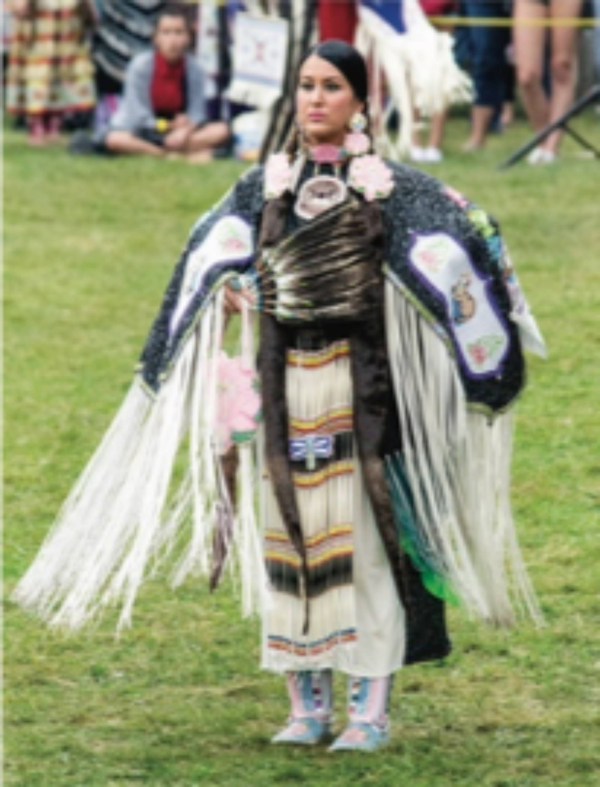 A woman wearing a traditional native outfit at a Pow Wow